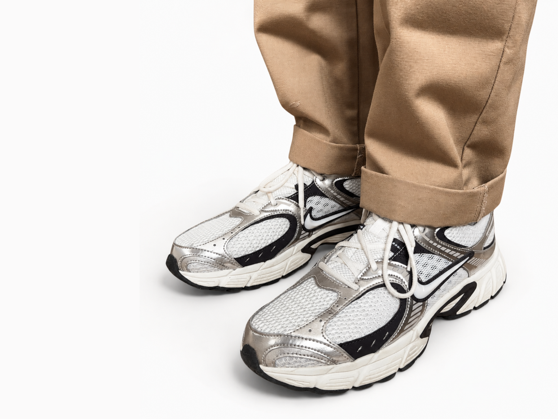 White and black nike sneakers with White Ondorq Elevate height increasing insole inside worn with brown pants on a white background.