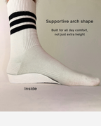 A close-up of a foot wearing a white Öndörq Elevate Invisible height Insole for men, shown against a plain beige background with text describing its supportive arch shape and comfort.