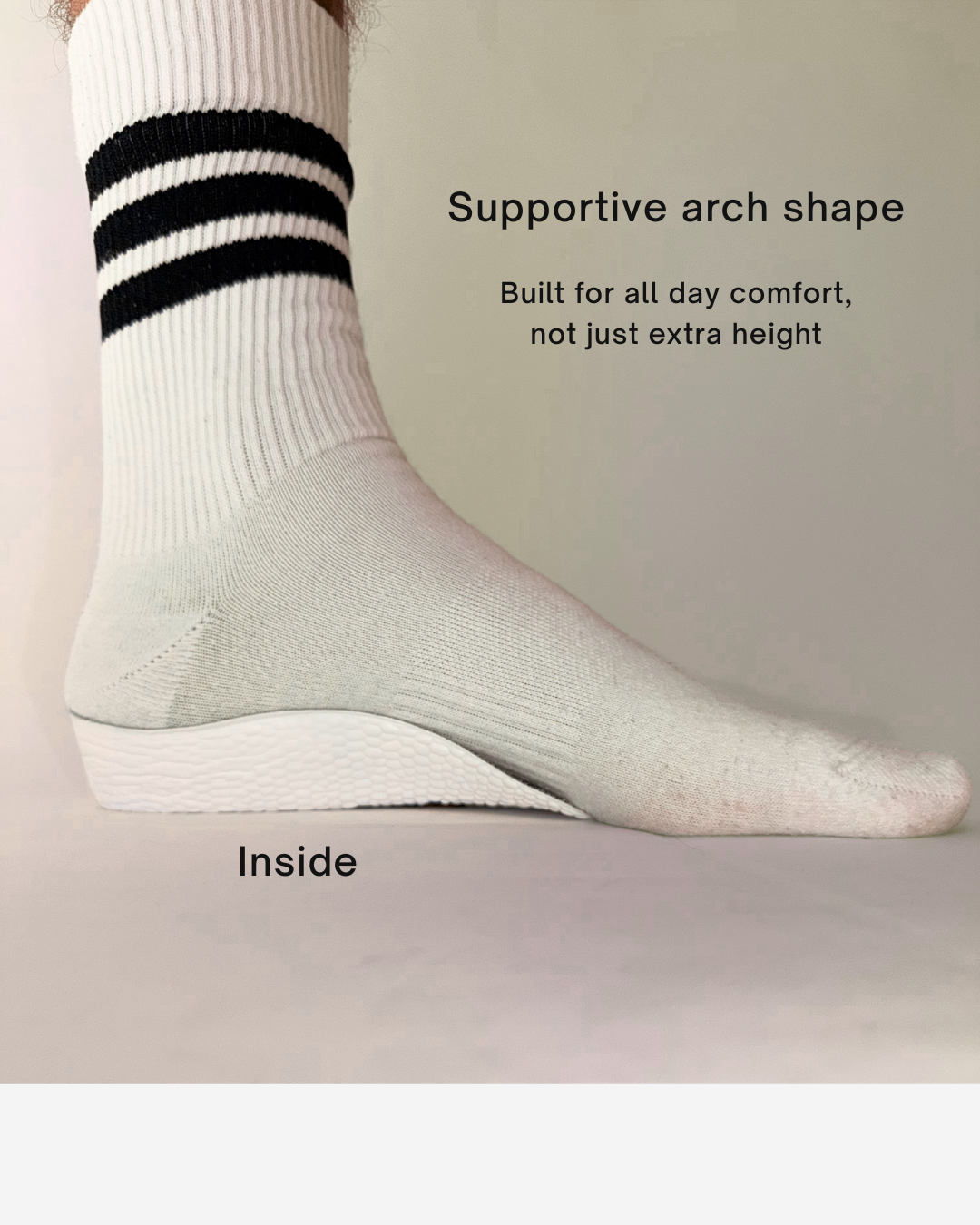 A close-up of a foot wearing a white Öndörq Elevate Invisible height Insole for men, shown against a plain beige background with text describing its supportive arch shape and comfort.
